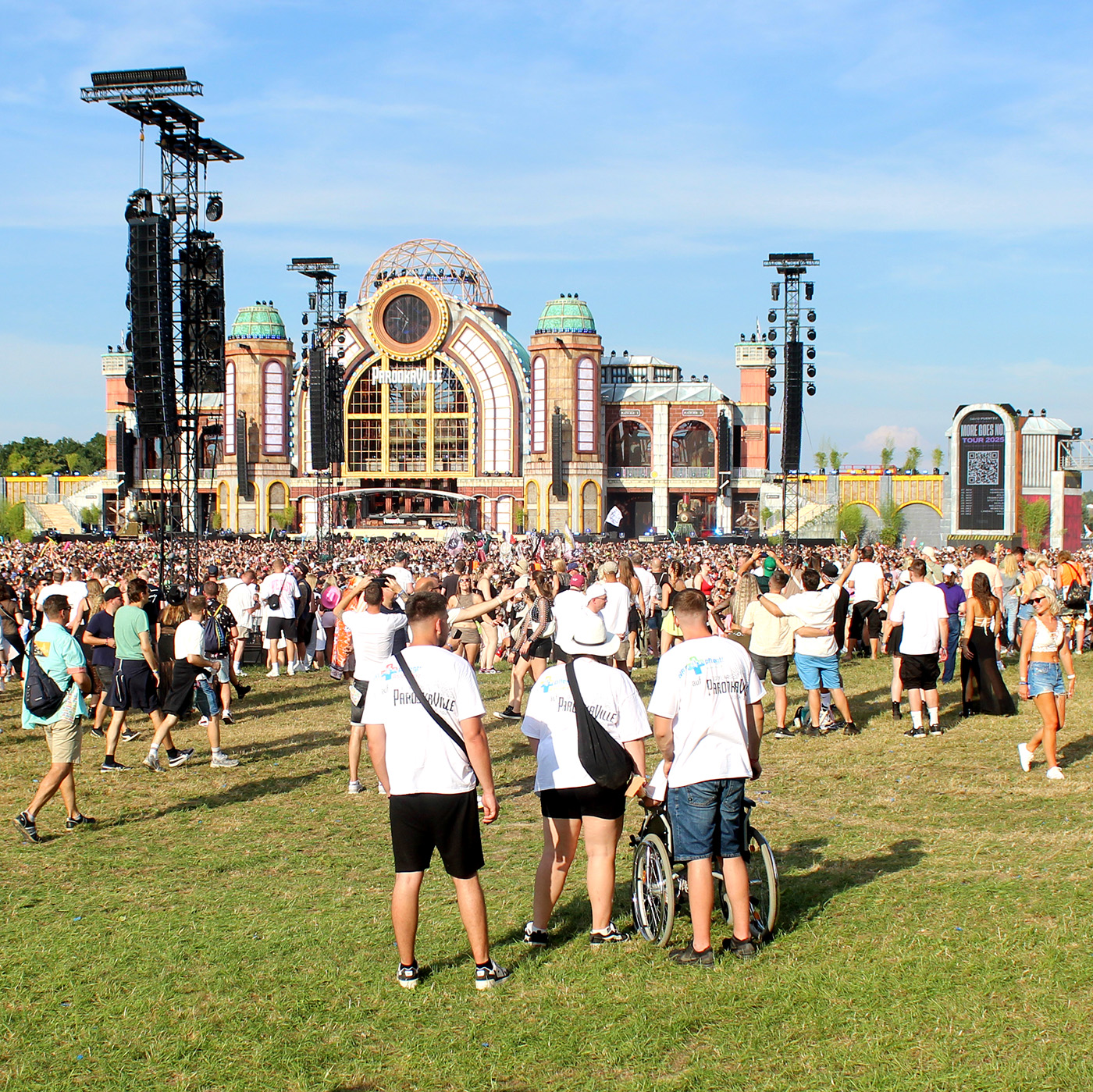 Das Bild zeigt unsere Reisegruppe auf einem Festivalgelände. Eine Teilnehmerin benötigt einen Rollstuhl.